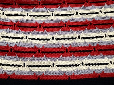 Lot 2119 - Pair of handknitted covers, red, white and black wool diamond cable design. 200cm x 160 cm approximately. Plus a crochet table cloth and mats. 180cm x 140cm approximately.