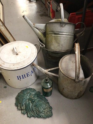 Lot 306 - Vintage enamelled bread bin with cover, two old watering cans and bucket, a green man mask wall plaque and an old medicine bottle