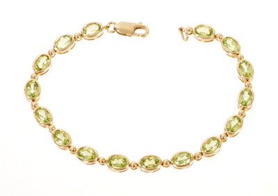 Lot 462 - 9ct gold peridot bracelet with a line of 16 oval mixed cut peridots in rub-over setting