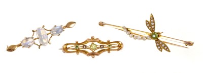 Lot 471 - Three Edwardian 9ct gold and gem-set brooches to include a peridot and seed pearl dragonfly brooch, another peridot and seed pearl brooch and a moonstone brooch (3)