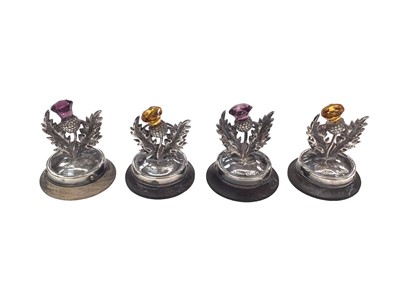 Lot 224 - Set of four Edwardian silver gem set thistle menu holders on wooden bases (Birmingham 1907), 4.5cm high