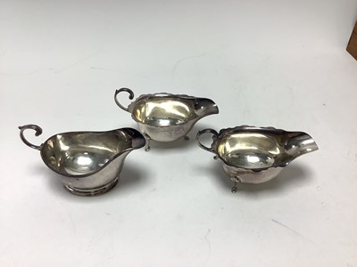 Lot 224 - Pair 1920s silver sauce boats of conventional form with open scroll handles on pad feet (Chester 1927) marks rubbed , together with one other sauce boat (Birmingham 1957) Adie Bros. Ltd. All at...