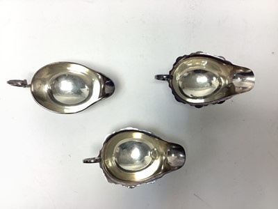 Lot 224 - Pair 1920s silver sauce boats of conventional form with open scroll handles on pad feet (Chester 1927) marks rubbed , together with one other sauce boat (Birmingham 1957) Adie Bros. Ltd. All at...