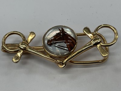 Lot 403 - Vintage yellow metal and Essex crystal tie clip with a central Essex crystal disc depicting a race horse in a yellow metal mount in the form of a horse bit, 50mm