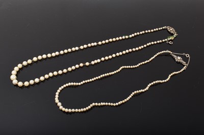 Lot 414 - Two cultured pearl necklaces, one with a graduated string measuring approximately 7.7mm to 2.7mm on a 9ct gold diamond set clasp, 54cm long and another similar on a silver marcasite clasp