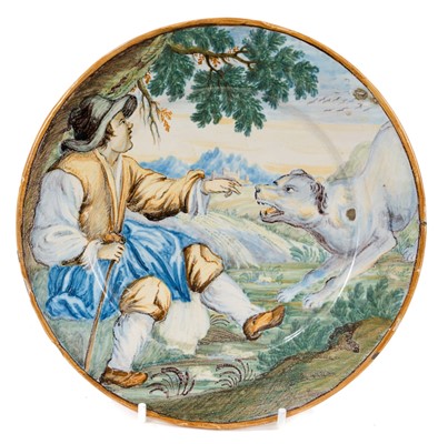 Lot 26 - Small Italian majolica dish, probably 18th century Castelli, painted with a shepherd and his dog, old collection label verso, 17.5cm diameter