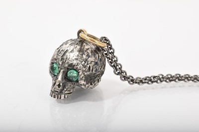 Lot 495 - Silver novelty pendant in the form of a skull with two emerald cabochon eyes and gold suspension ring on a silver chain, London hallmarks