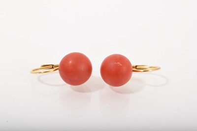 Lot 496 - Pair of coral earrings each with a 11mm diameter coral bead on 18ct gold fittings