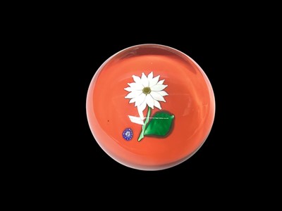 Lot 1163 - St Louis glass paperweight decorated with a flower on an orange ground, signed and dated 1992