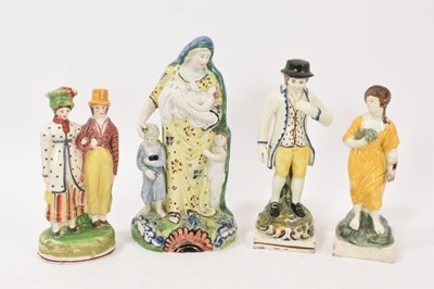 Lot 211 - Four early 19th century English pottery figures, including a pearlware figure of Charity, a pearlware couple on an oval base, and two Prattware figures on square bases