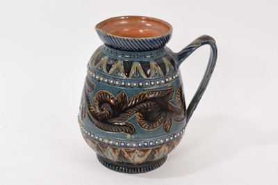 Lot 258 - Doulton Lambeth stoneware jug, decorated in blue and brown tones with scrollwork and foliage by Arthur Barlow, marks to base, 17cm high