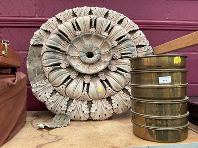 Lot 717 - A large plaster flower head on a wooden base, together with a set of brass sieves, and a leather case