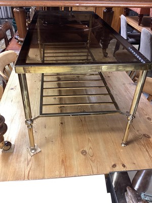 Lot 1377 - Brass coffee table with smoked glass top and magazine rack undertier, 105.5cm wide, 46cm deep, 41.5cm high