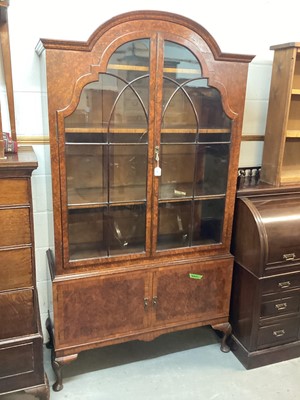 Lot 1397 - Early 20th century burr walnut veneered two height bookcase with shelves above enclosed by two arched glazed doors, and cupboards below, 109.5cm wide, 40cm deep, 199cm high