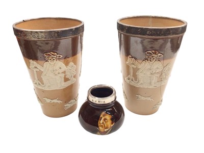 Lot 366 - Pair of Doulton Lambeth beakers with silver rims and a Royal Doulton silver mounted Dickens pot (3)