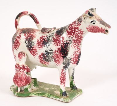 Lot 282 - Pearlware cow creamer, circa 1820, with purple and black sponged decoration, the back legs tied together, on green sponged base, 13.5cm high