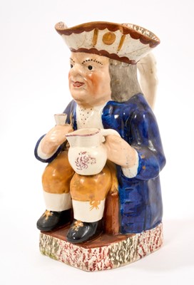 Lot 305 - Antique Staffordshire Toby jug, circa 1840, holding jug and separate beaker, with sponged decoration to base and hat, figural handle, 25cm high