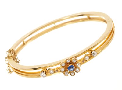 Lot 643 - Late Victorian gold hinged bangle with a blue sapphire and seed pearl flower flanked by two old cut diamonds