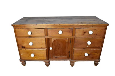 Lot 1503 - Victorian pine dresser base, having seven drawers about the recessed central cupboard, each with ceramic handles, on spool feet, 140cm wide x 53cm deep x 80cm high