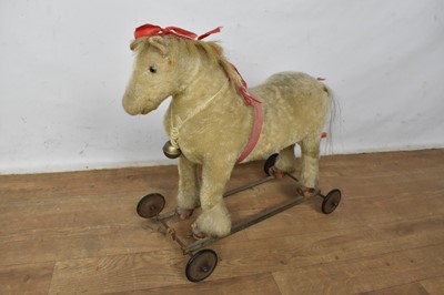 Lot 1524 - Antique child's push along horse, with mohair finish, on wheeled base, approximately 55cm long