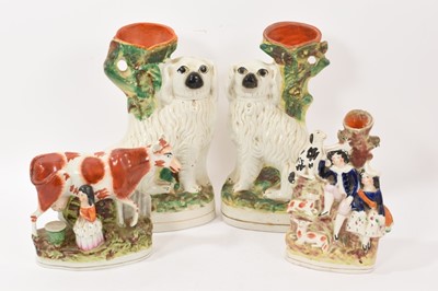 Lot 323 - Pair of Victorian Staffordshire spaniel spill vases, 33cm high, together with a Staffordshire cow and milkmaid group, and another spill vase (4)