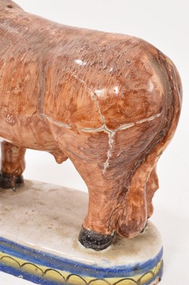 Lot 40 - Tin-glaze earthenware model of a bull, probably Dutch, polychrome painted on an oval base, 20.5cm high