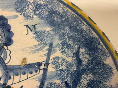 Lot 328 - A rare English delft ware Duke of Marlborough charger, probably Bristol, circa 1710, decorated with a full length portrait of the Duke wearing a suit of armour, yellow cloak and sash, with blue...