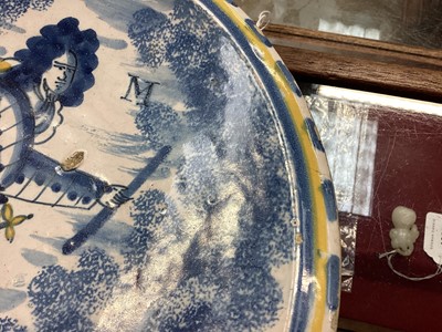 Lot 328 - A rare English delft ware Duke of Marlborough charger, probably Bristol, circa 1710, decorated with a full length portrait of the Duke wearing a suit of armour, yellow cloak and sash, with blue...