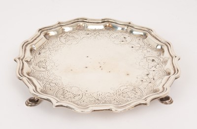 Lot 522 - George II silver waiter of circular form with pie crust border and engraved decoration, raised on three hoof feet, (London 1734), maker John Tuite, 8ozs, 15.5cm in diameter.