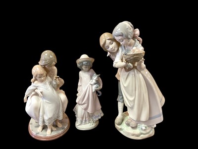 Lot 1256 - Three Lladro porcelain figures - mother and child, girl holding a cat and couple carrying fruit (two are boxed, but one is the wrong box)