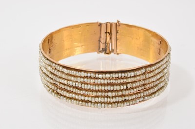 Lot 222 - Eastern yellow metal and seed pearl bangle