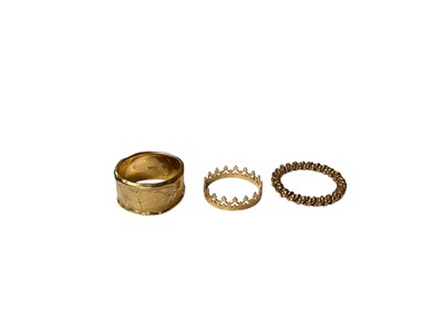 Lot 39 - Three yellow metal rings to include a thick abstract band (stamped 375), crown ring (stamped 14K) and a rope twist band
