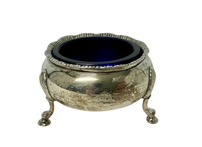 Lot 181 - Victorian silver cauldron salt with gadrooned rim, engraved crest and three scroll legs, with blue glass liner (London 1894) 2.7ozs