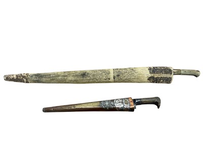 Lot 970 - Two 19th century Indian Kyber knives with T back blades in sheaths, one mounted with Border Regiment badge (2)