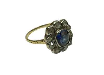 Lot 229 - Antique sapphire and diamond flower-head cluster ring with a central oval mixed cut blue sapphire surrounded by a border of ten rose cut diamonds in rub-over white metal setting, on gold gallery...