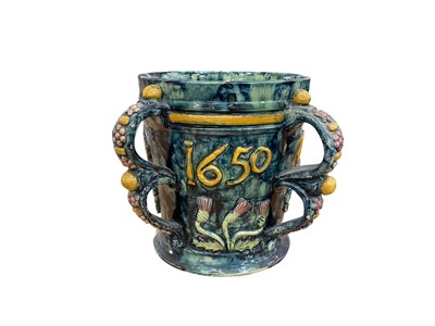 Lot 12 - Castle Hedingham Edward Bingham blue glazed pottery four handled jug / loving cup with applied floral decoration and 1650, the base marked No 22, E.W Bingham, 19cm high