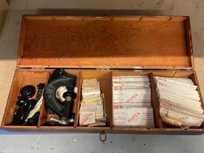 Lot 82 - A vintage wooden case containing unused spare watch glassses in packets and a watch glass press.