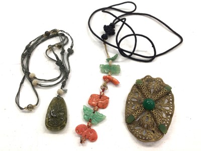 Lot 1077 - Chinese carved hardstone pendant on fabric cord with seed pearl and glass panels, together with a carved green hardstone and coral panel necklace