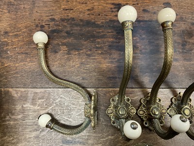 Lot 225 - Set of six large Victorian brass coat hooks with ceramic terminals, plus one other (7)