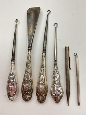 Lot 1035 - Three silver handled button hooks, silver handled shoe horn, one silver pencil and one other silver plated pencil (6)