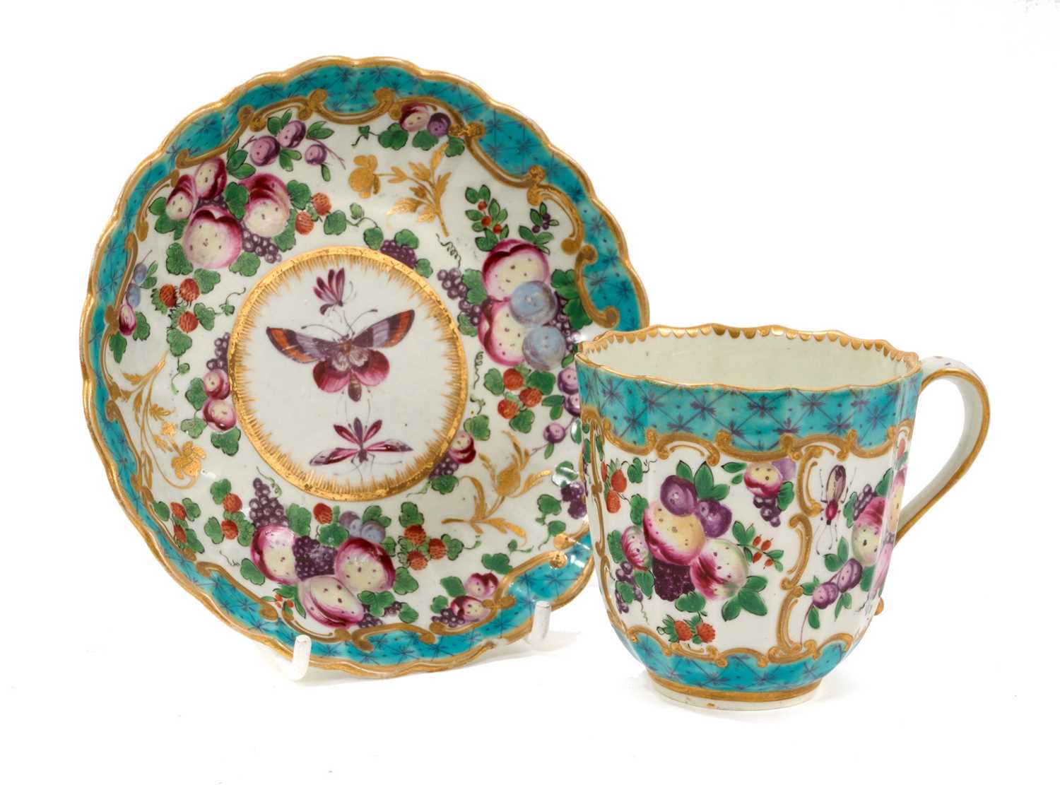 Lot 28 - An unusual Worcester fluted porcelain cup and saucer, circa 1770, painted in enamels with fruit and insects, with gilt and turquoise scroll borders, the saucer 13.5cm diameter