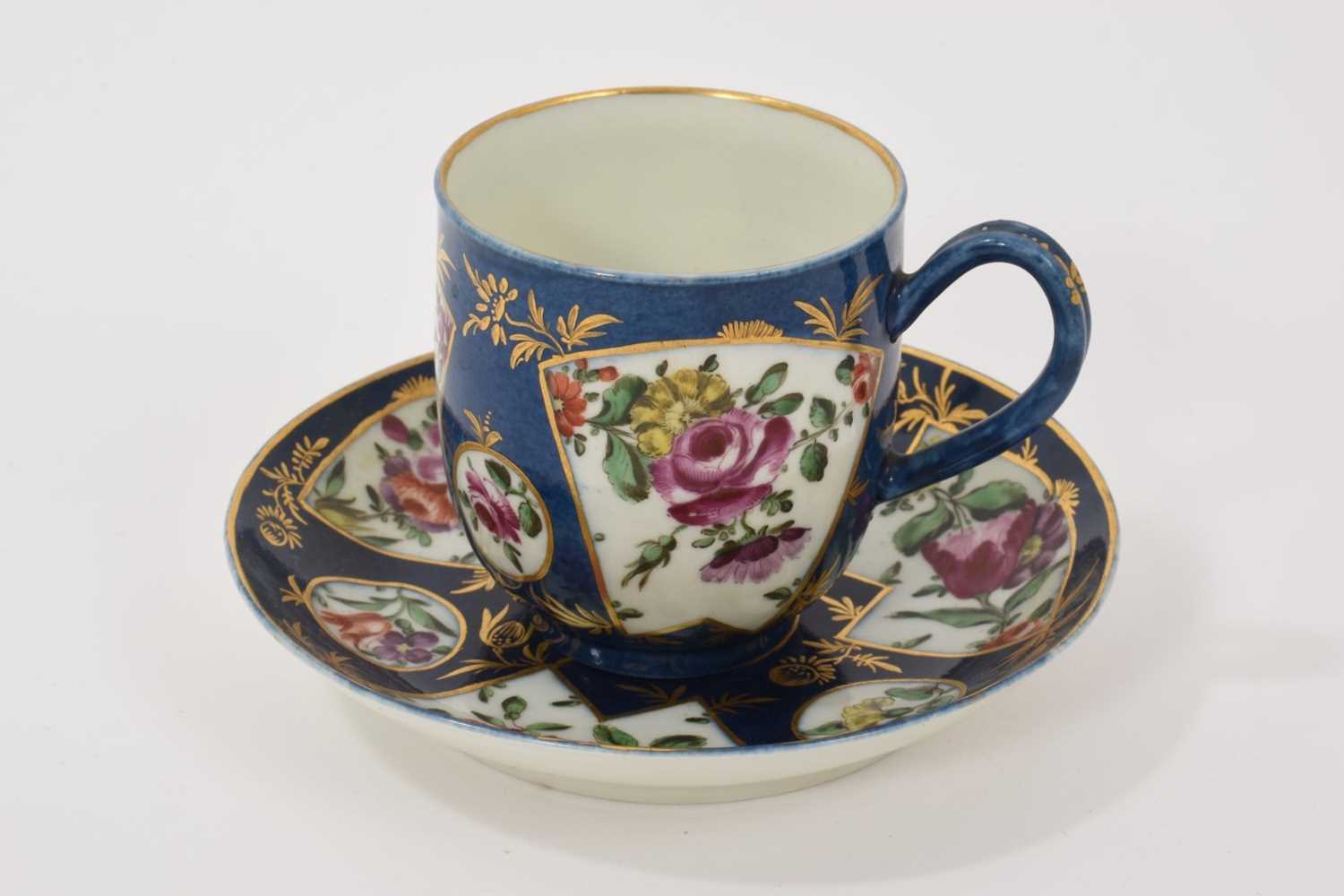 Lot 36 - A Worcester coffee cup and saucer, circa 1765, polychrome painted with flowers in fan-shaped panels, on a powder blue ground, the saucer 11.5cm diameter