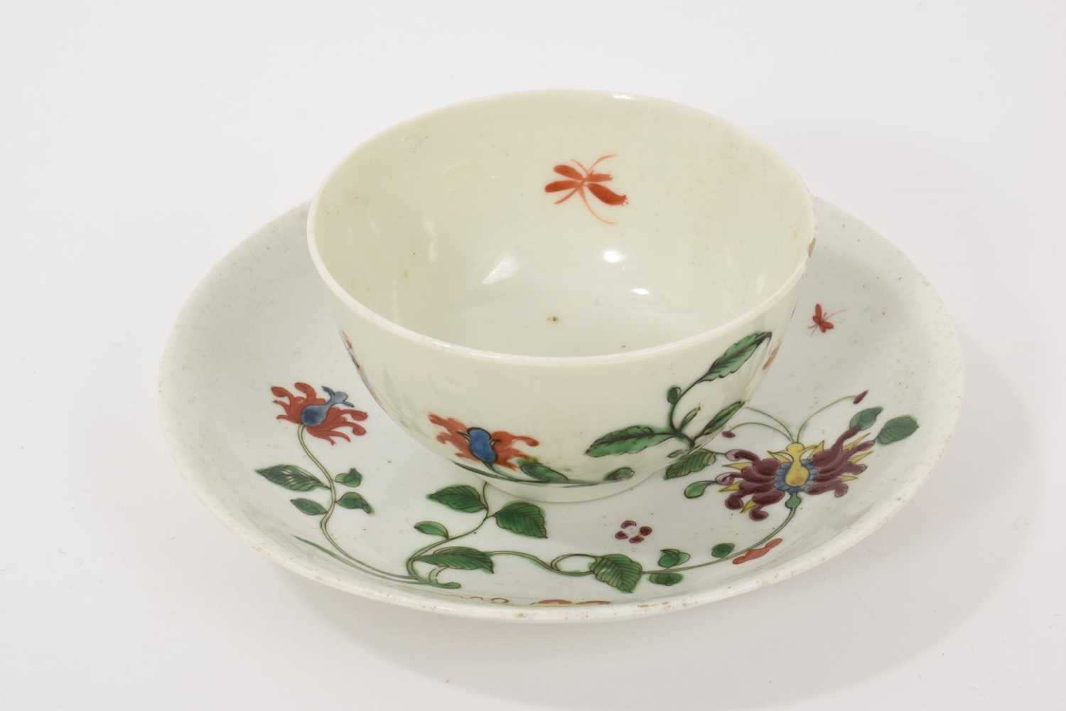 Lot 11 - A Worcester Hibiscus pattern tea bowl and saucer, circa 1758, decorated with scroll emblem, large honeysuckle flower, trailing vines and insects, the saucer 12cm diameter