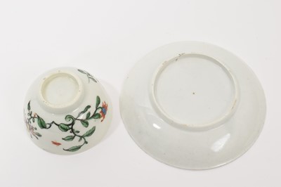 Lot 11 - A Worcester Hibiscus pattern tea bowl and saucer, circa 1758, decorated with scroll emblem, large honeysuckle flower, trailing vines and insects, the saucer 12cm diameter