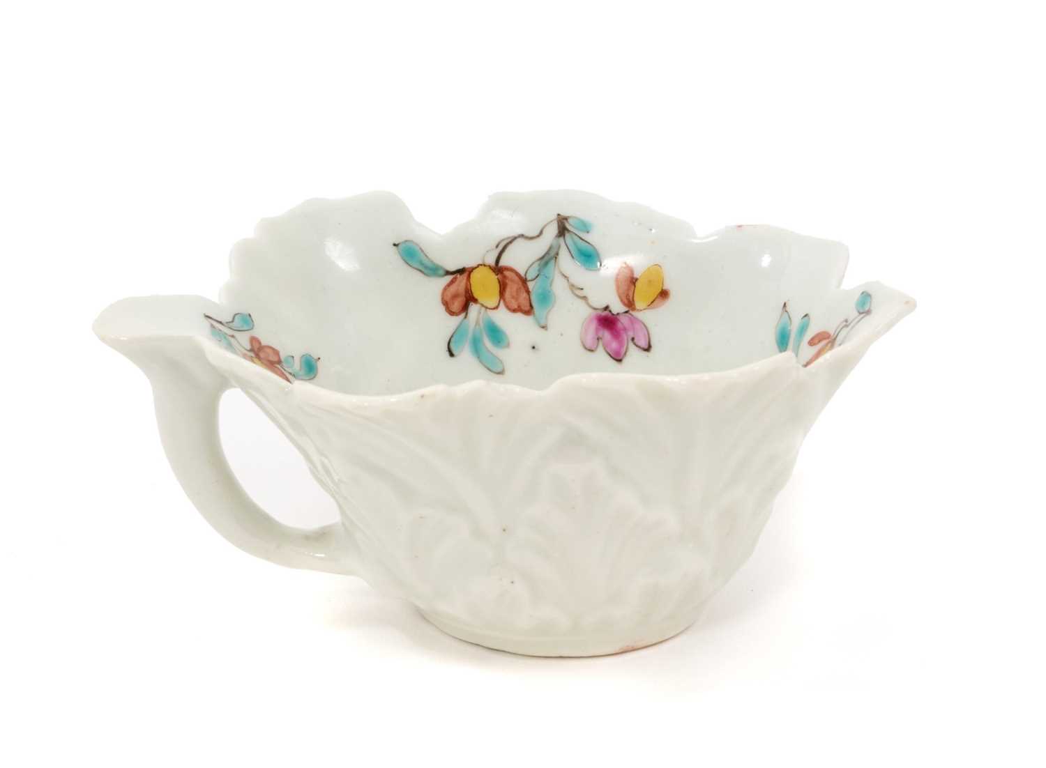 Lot 12 - A Worcester polychrome leaf-shaped butterboat, circa 1758, with branch handle, painted to the well with scattered polychrome sprigs and flowers, the exterior moulded with overlapping leaves, 8.5...