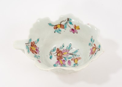 Lot 12 - A Worcester polychrome leaf-shaped butterboat, circa 1758, with branch handle, painted to the well with scattered polychrome sprigs and flowers, the exterior moulded with overlapping leaves, 8.5...