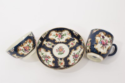 Lot 38 - A Worcester trio, circa 1760-70, comprising coffee cup, tea bowl and saucer, polychrome painted with floral sprays in gilt scrollwork panels, on a blue scale ground, square marks to bases