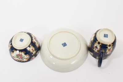 Lot 38 - A Worcester trio, circa 1760-70, comprising coffee cup, tea bowl and saucer, polychrome painted with floral sprays in gilt scrollwork panels, on a blue scale ground, square marks to bases