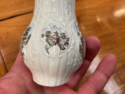 Lot 7 - A very rare early Worcester cream jug, circa 1754, finely moulded with a strap-fluted design and scrollwork cartouches painted with chinoiserie landscapes, echoing the style of Herold's designs...
