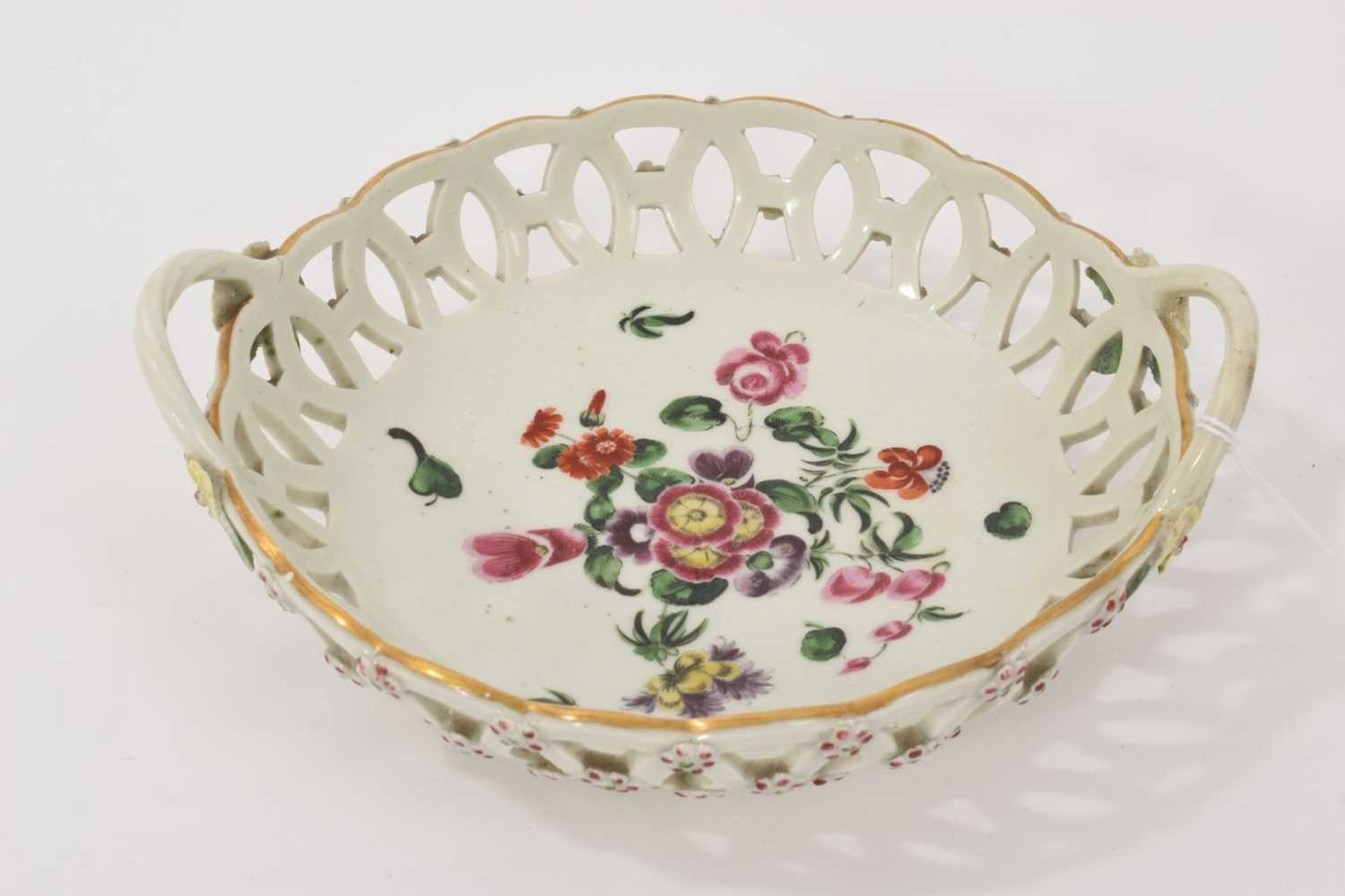 Lot 20 - A Worcester round basket, circa 1770, polychrome painted with flowers, the handles with flower and leaf terminals, the outside with applied florets picked out in puce and green, 17cm wide